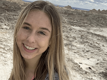Allison poses at the base of a natural rock archway in Arizona.