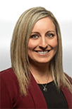 Christina Pearson has blonde shoulder length hair that is straight and parted to the side. She wears a maroon blazer with a black blouse and a gold necklace.