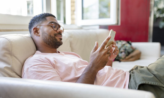 Man laying on couch looking at cellphone.