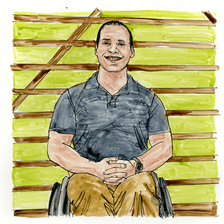 Dan McCoy leans back in his wheelchair against an office cubicle desk.