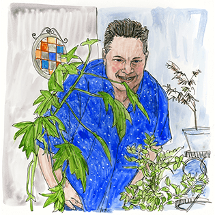 Mark stands behind two green plants. 