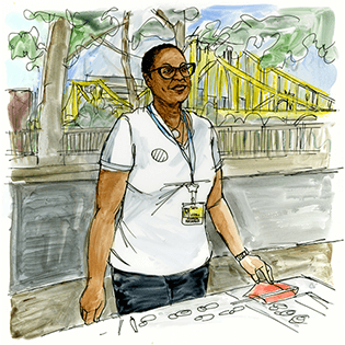 Sara stands outside in front of a yellow bridge. 