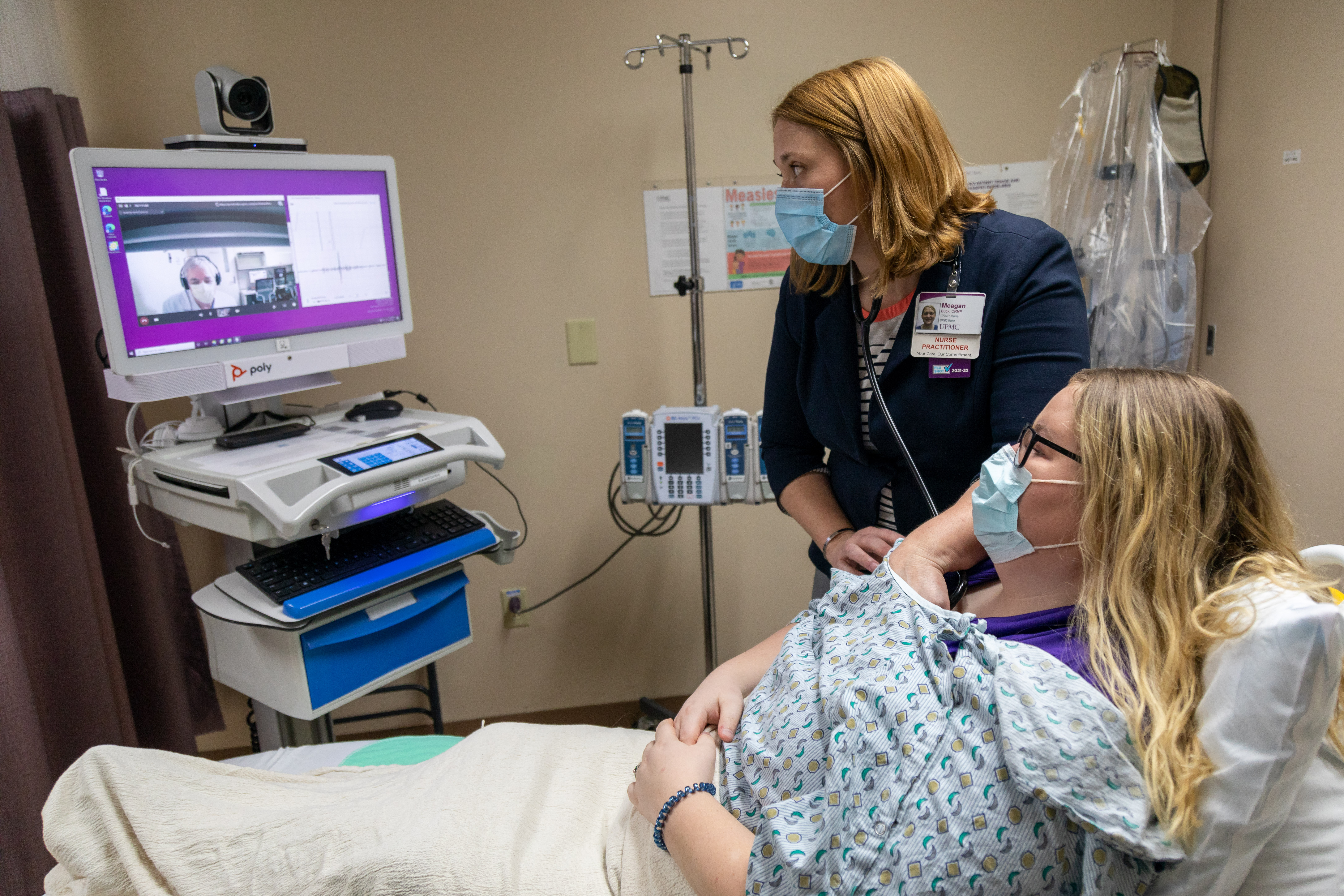 A photo of a healthcare professional with a patient on a virtual call with another healthcare professional.