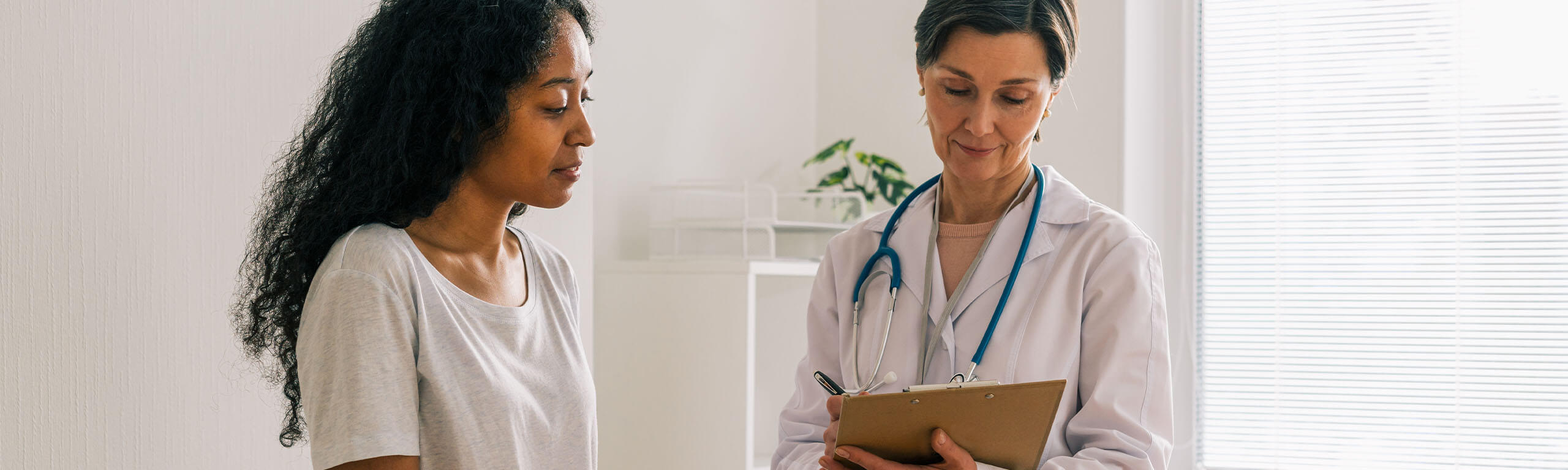 Female doctor reviews medical chart with female patient