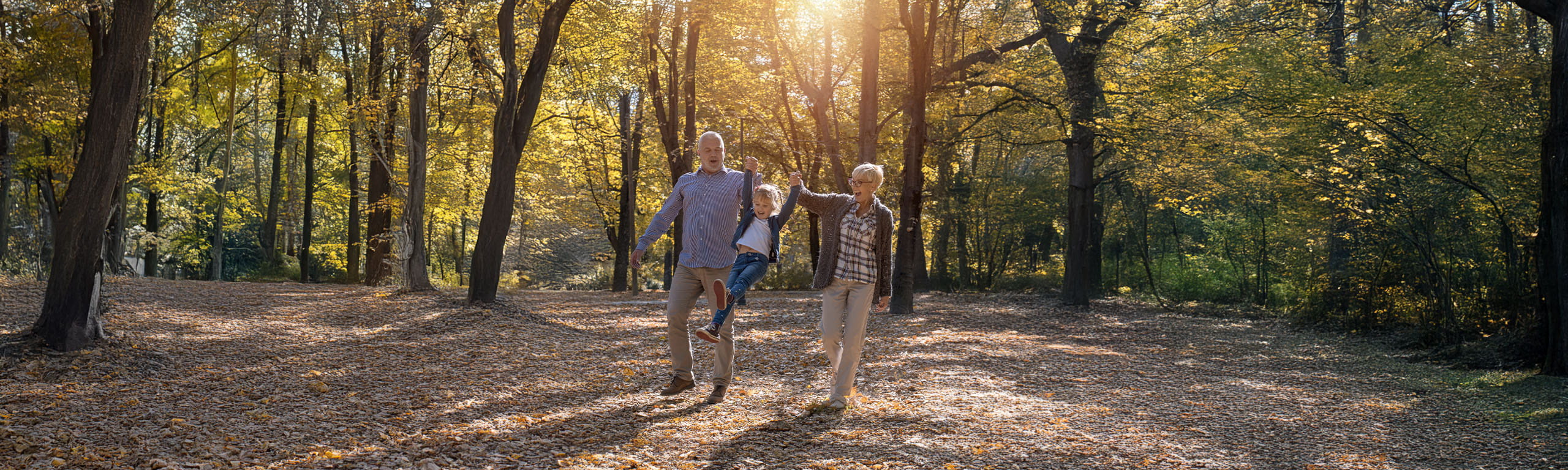 Older couple walking through woods playing with child