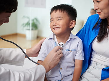 Pediatric doctor listing to child's lungs